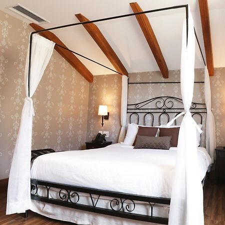 Buona Vitta Gramado Resort & Spa By Gramado Parks Екстериор снимка The photo shows a beautifully designed bedroom featuring a four-poster bed with a metal frame and flowing white curtains. The bed is adorned with white bedding and brown decorative pillows. The room has wooden beams on the ceiling and is decorated wi