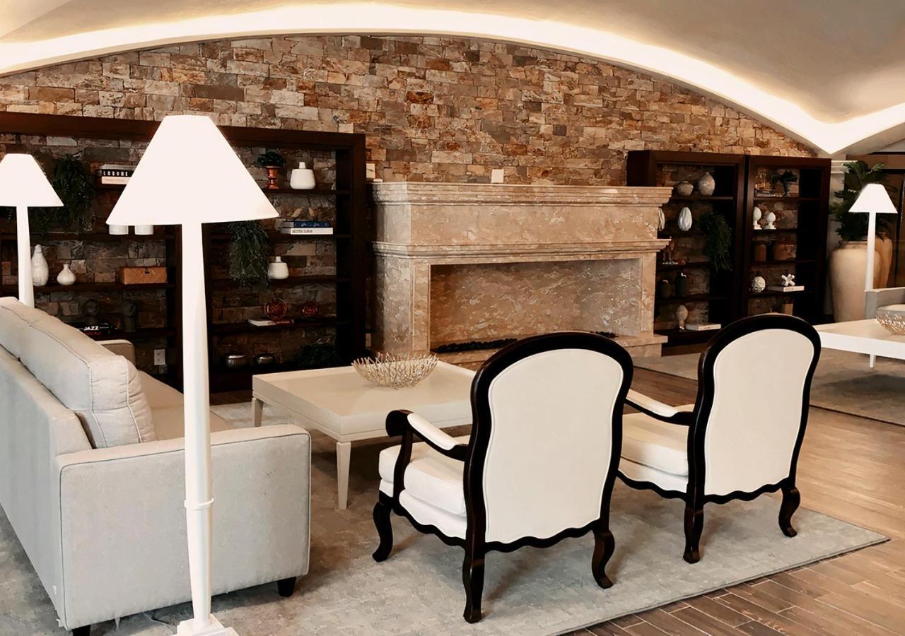 Buona Vitta Gramado Resort & Spa By Gramado Parks Екстериор снимка The photo shows a stylish living room with a modern design. In the center, there is a light-colored sofa and two elegant white armchairs with black wooden frames. A coffee table is placed in front of the sofa. Behind them, there is a large, decorativ
