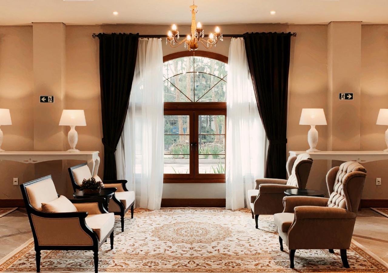 Buona Vitta Gramado Resort & Spa By Gramado Parks Екстериор снимка The photo shows an elegantly styled living room. There are two armchairs and a sofa arranged comfortably around an intricate area rug. Large windows are adorned with sheer white curtains and dark curtains, allowing natural light to fill the space. A 