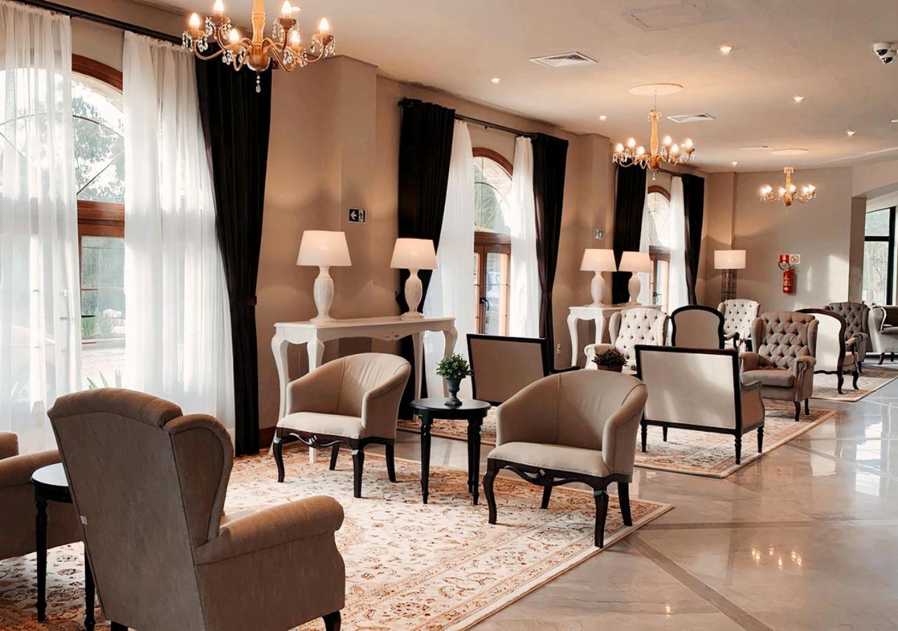 Buona Vitta Gramado Resort & Spa By Gramado Parks Екстериор снимка The photo depicts a stylish and sophisticated lounge area. It features several elegant chairs and sofas, arranged around small tables on a decorative rug. The room is well-lit with natural light coming in through large windows dressed with flowing wh