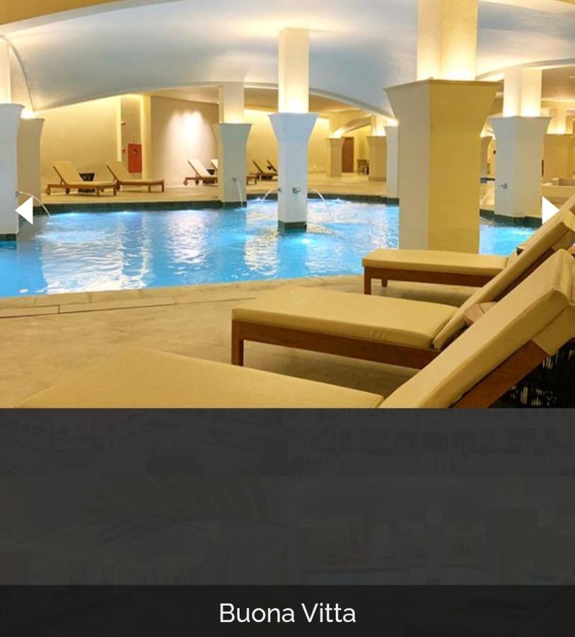 Buona Vitta Gramado Resort & Spa By Gramado Parks Екстериор снимка The photo shows a tranquil indoor pool area, featuring a large swimming pool with clear blue water. Surrounding the pool are several lounge chairs made of light-colored wood, positioned for relaxation. The space is well-lit, with soft lighting highli