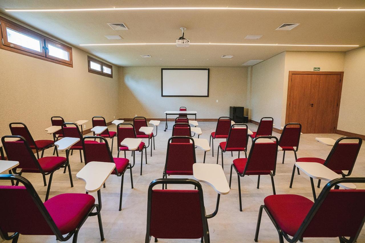 Buona Vitta Gramado Resort & Spa By Gramado Parks Екстериор снимка The photo shows a classroom or meeting room set up for a presentation or lecture. It features several rows of red chairs, each with a small writing surface attached. There is a blank screen mounted on the wall at the front of the room, likely for dis