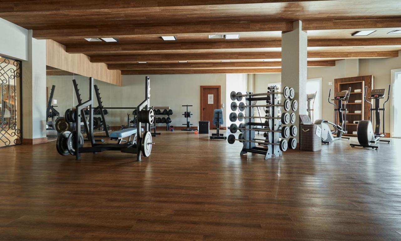 Buona Vitta Gramado Resort & Spa By Gramado Parks Екстериор снимка The photo shows a spacious gym with a wooden floor and wooden ceiling beams. Various pieces of gym equipment are visible, including weight benches and racks with weights. On one side, there are free weights organized on a rack, while other equipment 