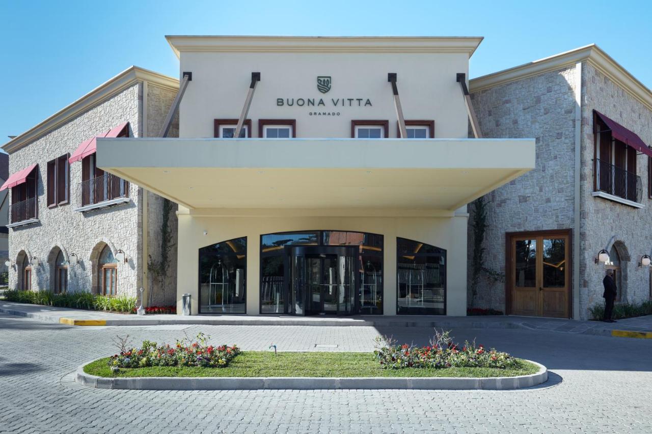 Buona Vitta Gramado Resort & Spa By Gramado Parks Екстериор снимка The photo shows a modern building with a prominent entrance marked by a large awning. The facade features a mix of stone and stucco materials, giving it an elegant and contemporary look. The name "BUONA VITTA" is displayed prominently above the entra