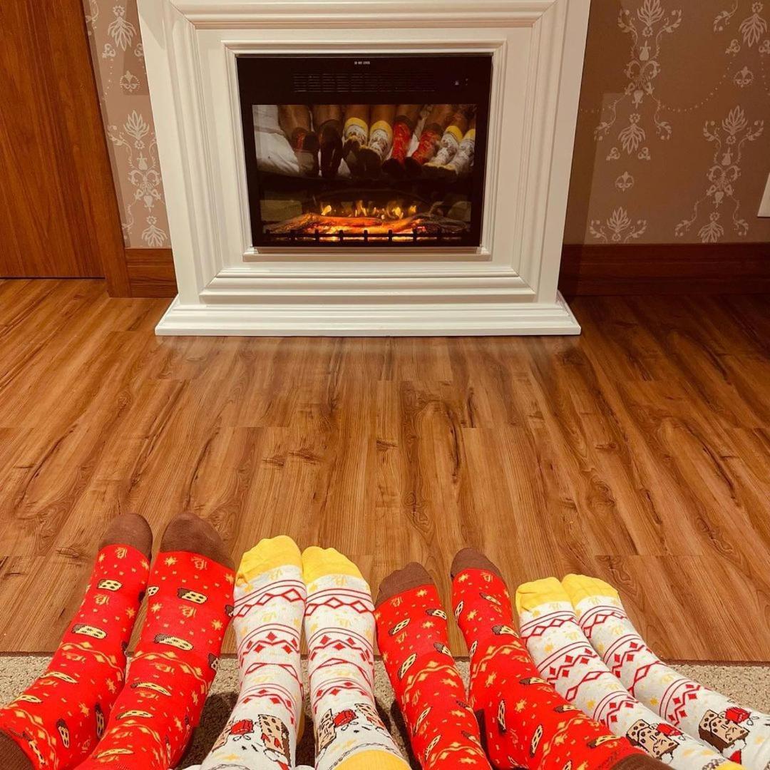 Buona Vitta Gramado Resort & Spa By Gramado Parks Екстериор снимка The photo shows a cozy indoor setting with a warm fireplace. In the foreground, several pairs of feet are displayed, each wearing brightly colored socks with various patterns. The socks include red, yellow, and white designs, contributing to a cheerf