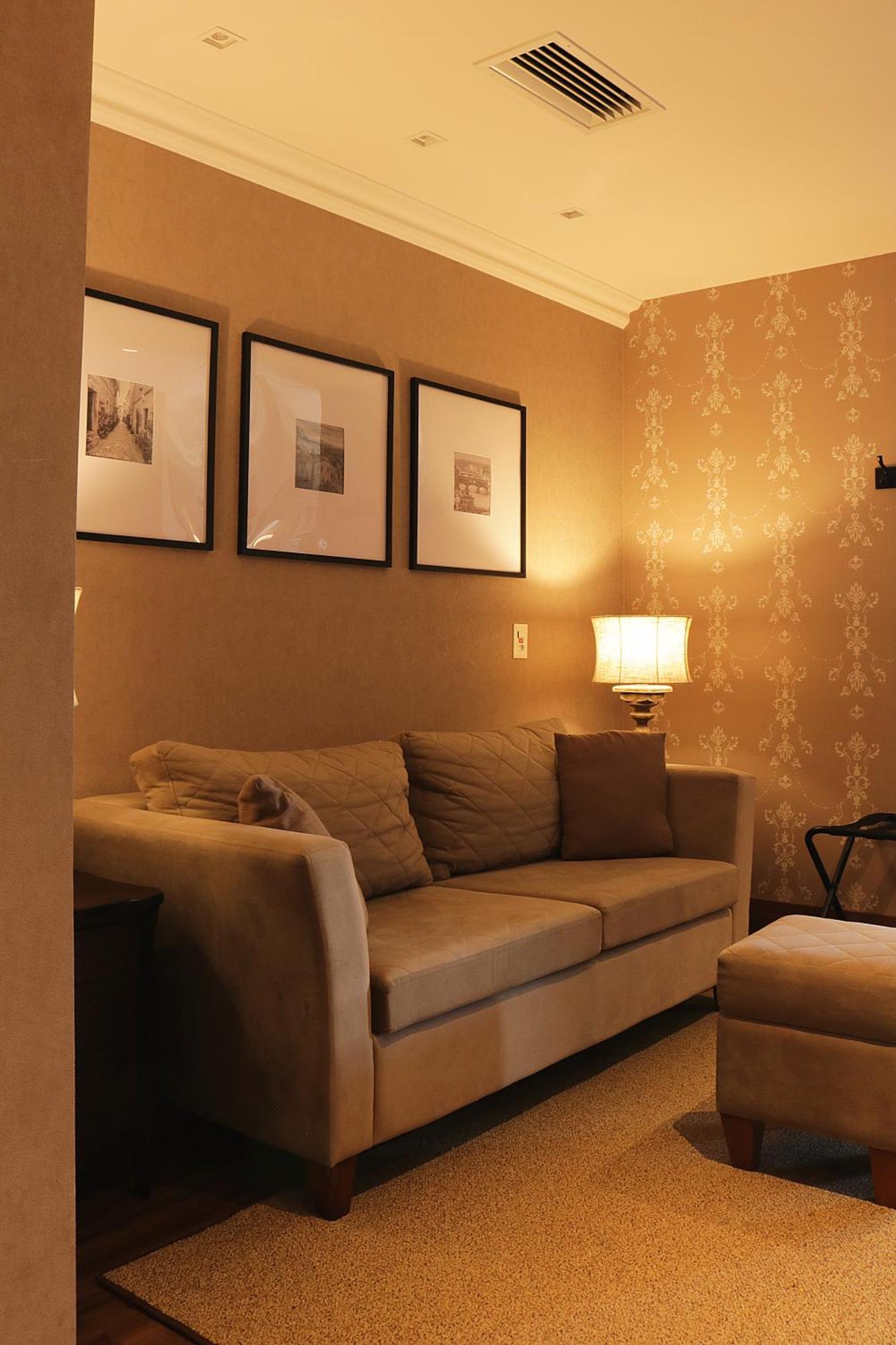 Buona Vitta Gramado Resort & Spa By Gramado Parks Екстериор снимка The photo shows a cozy living room setting. There is a light-colored sofa adorned with several cushions, positioned against a wall that has a subtle pattern. Above the sofa, there are three framed artworks or photographs hanging on the wall. To the s