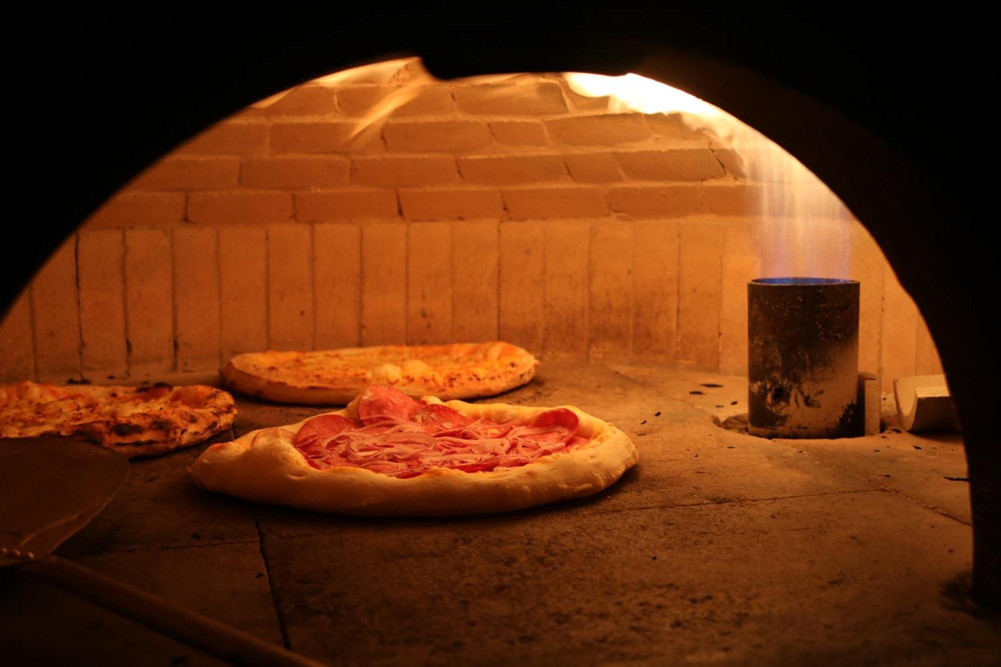 Buona Vitta Gramado Resort & Spa By Gramado Parks Екстериор снимка The photo shows a traditional pizza oven. Inside the oven, there are several pizzas placed on the stone surface. The pizzas appear to have various toppings, including what looks like cheese and possibly pepperoni. The oven has a warm, glowing ambianc