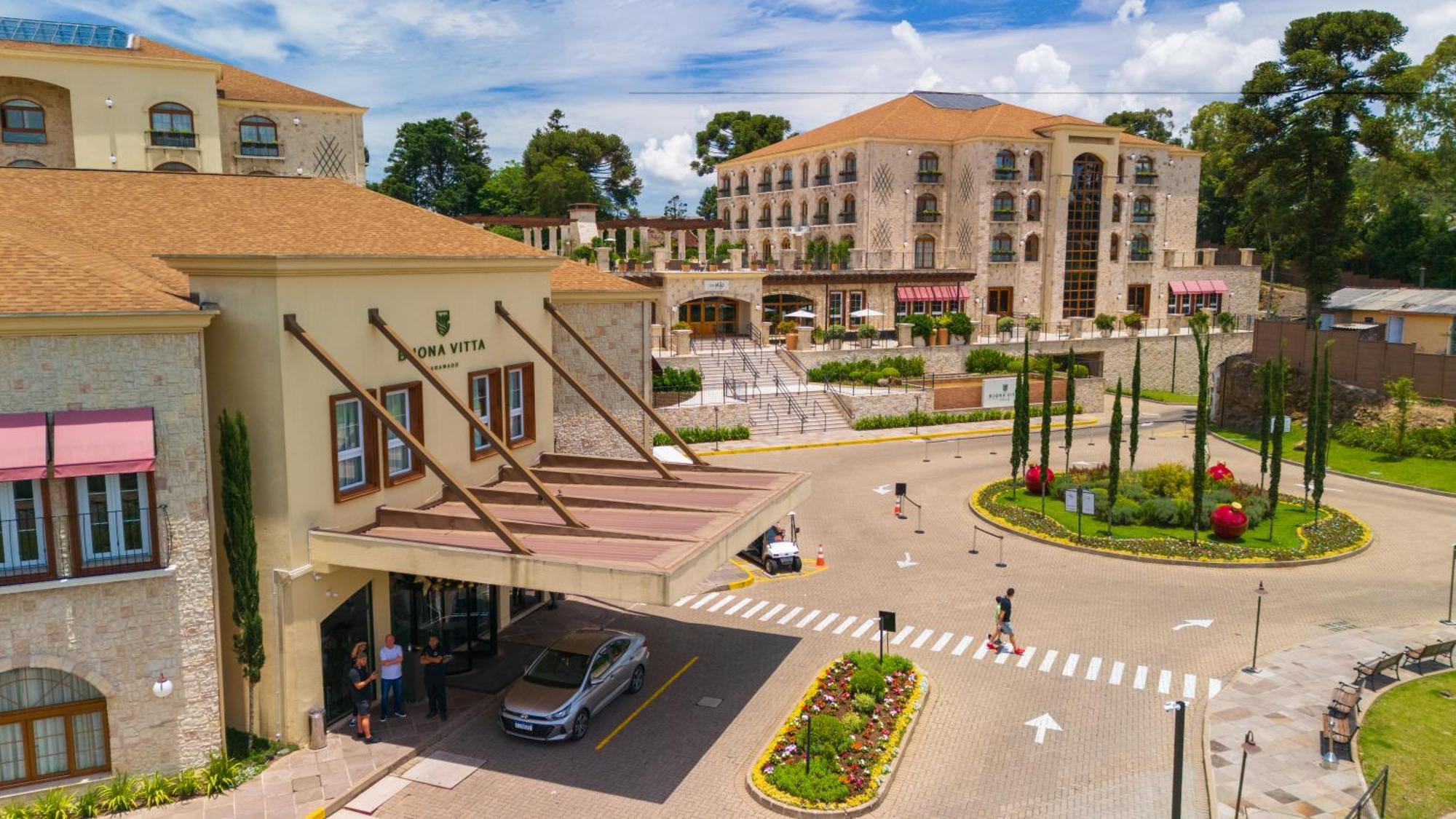 Buona Vitta Gramado Resort & Spa By Gramado Parks Екстериор снимка The photo shows a luxurious hotel or resort entrance, featuring a modern yet elegant architectural design. In the foreground, there is a covered entrance where vehicles are likely dropping off guests. The building has a stone facade and a welcoming e