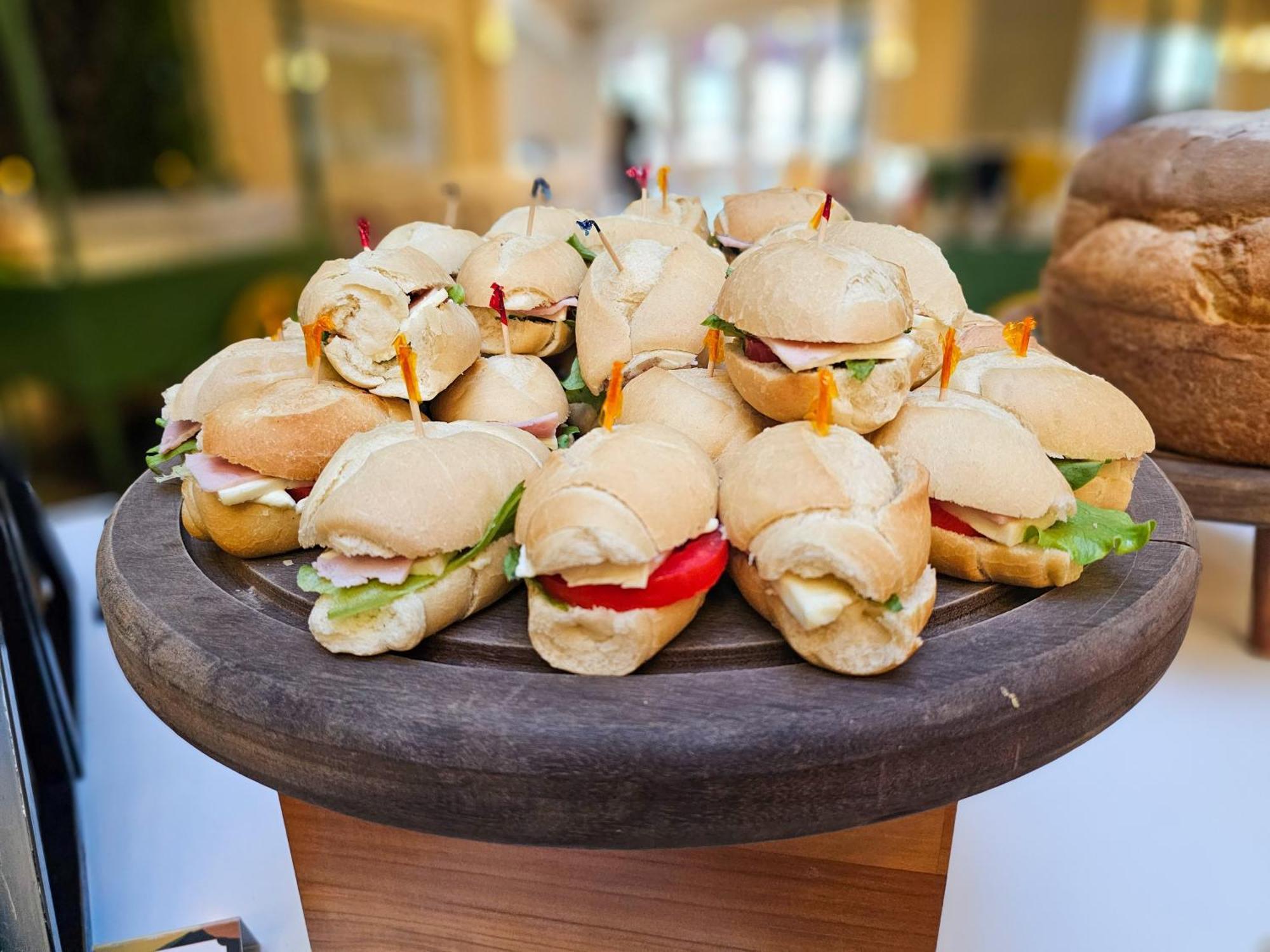 Buona Vitta Gramado Resort & Spa By Gramado Parks Екстериор снимка The photo shows a platter of small sandwiches, likely sliders, arranged neatly on a wooden serving tray. These sandwiches have various fillings, including what appears to be ham, lettuce, and tomato. They are garnished with colorful toothpicks, and t